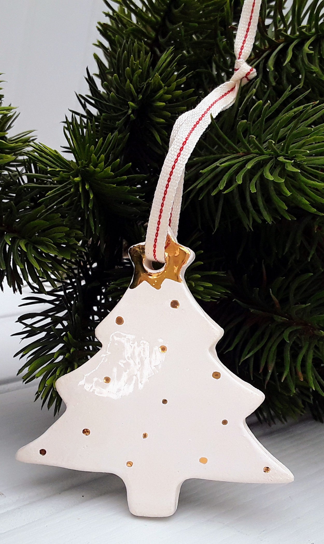 White ceramic Christmas tree ornament decorated with gold dots and topped with a gold star