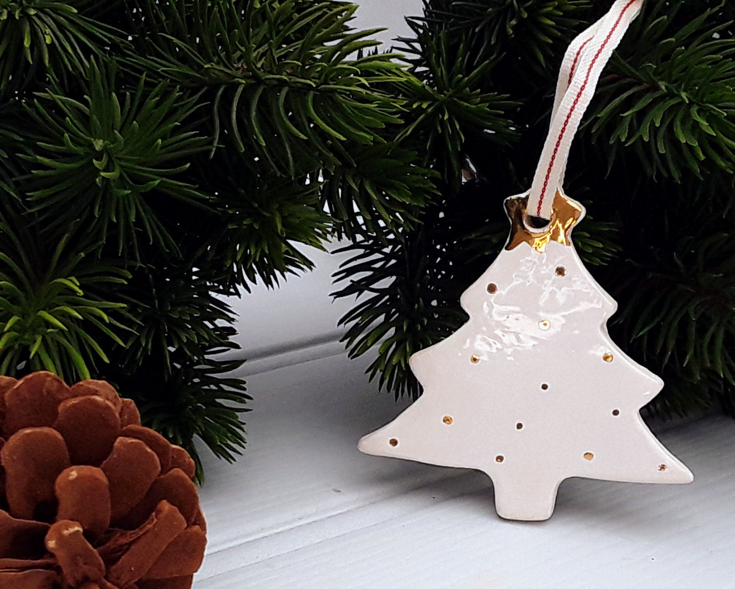 White ceramic Christmas tree ornament decorated with gold dots and topped with a gold star