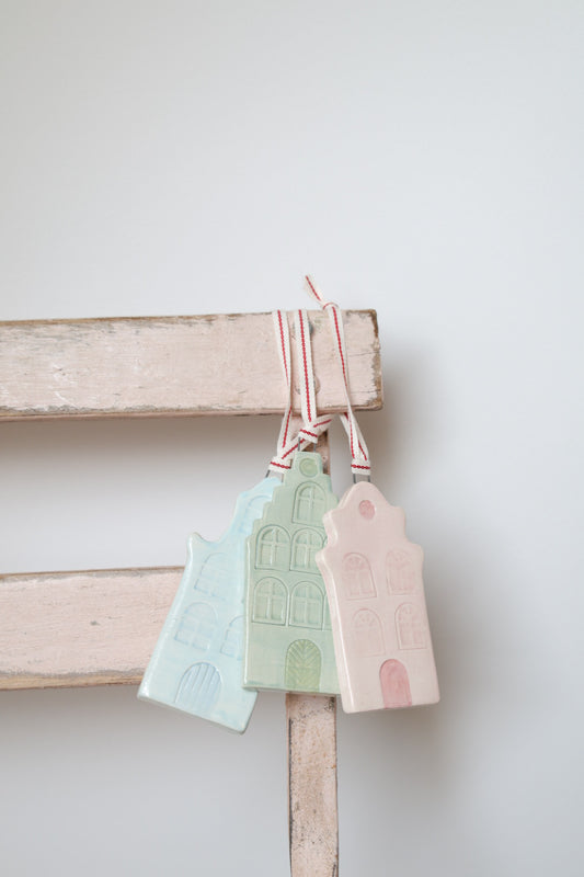 Three colourful ceramic  Christmas tree ornaments by Sea Bramble Ceramics are suspended gracefully on the corner of a chair.