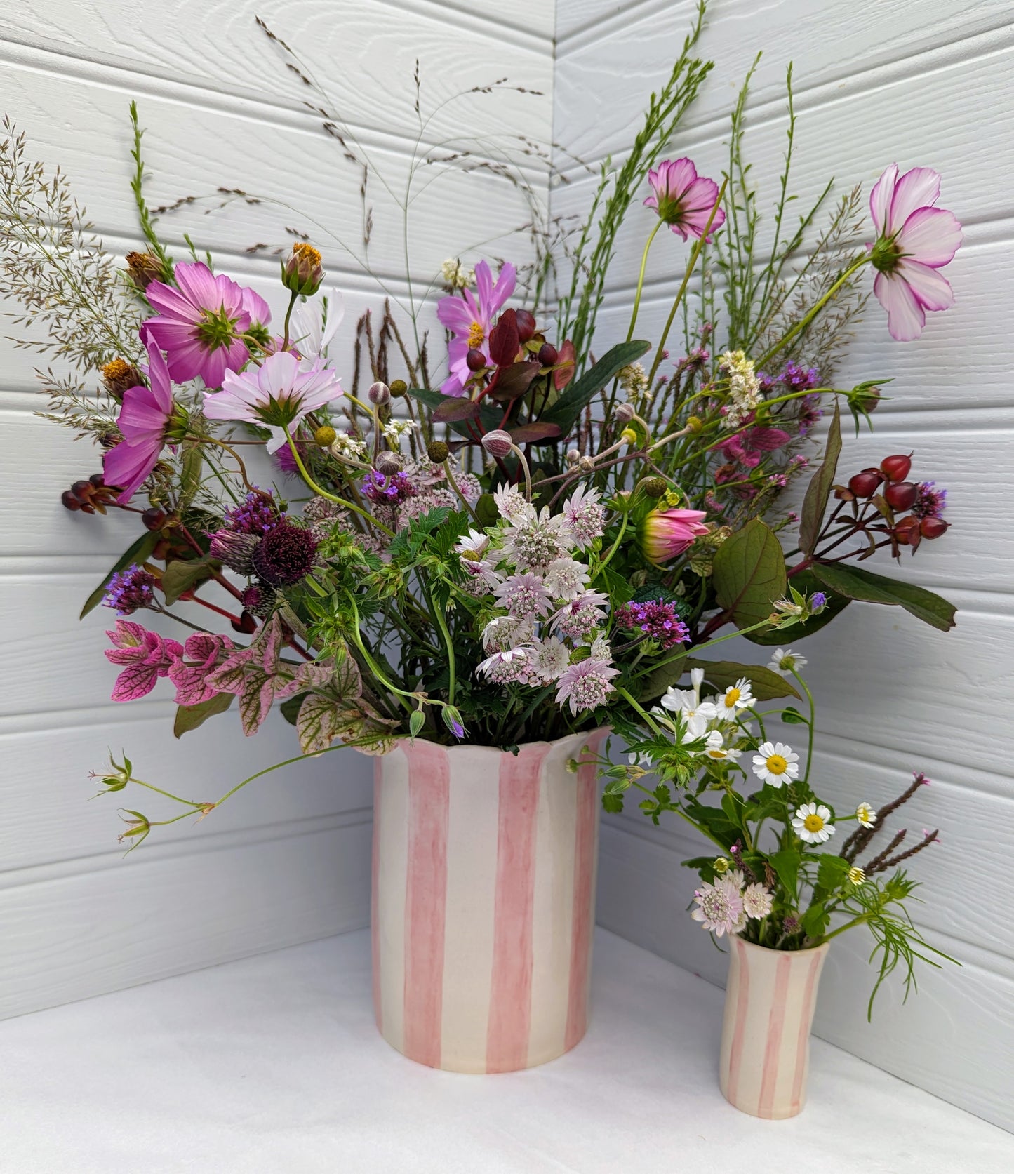 Sea Bramble Ceramics - Handmade, Extra-large, Stoneware vase from their Daisy vase range. With pink stripes and a scalloped top, this vase is ideal for fuller, larger flower arrangements. Shown in comparison with a Sea Bramble Ceramics Sweet pea vase.