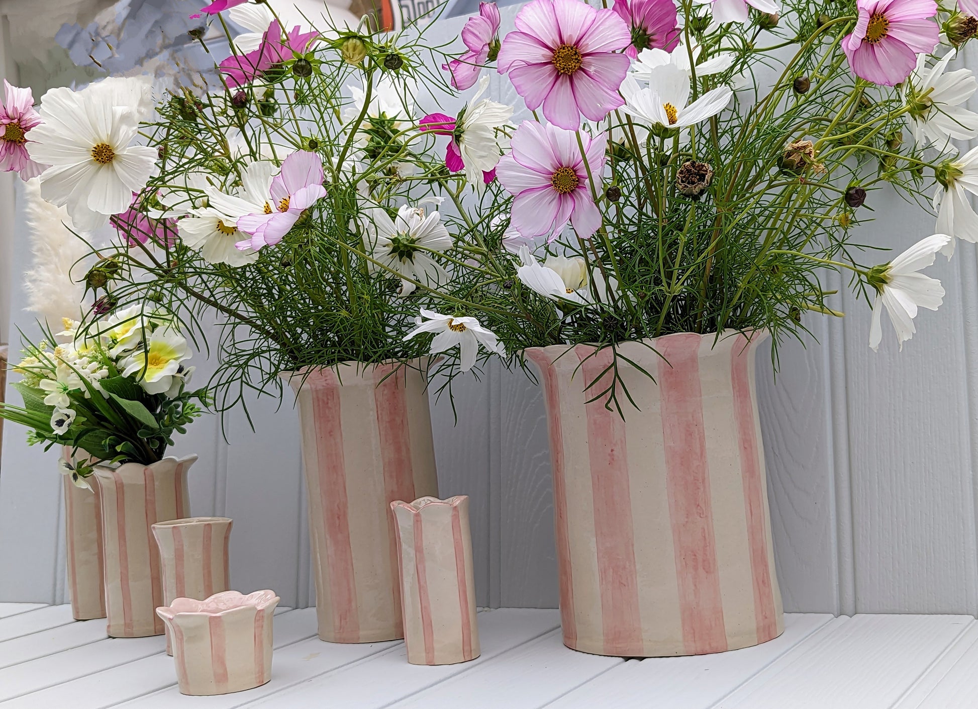 Sea Bramble Ceramics - Handmade, Extra-large, Stoneware vase from their Daisy vase range. With pink stripes and a scalloped top, this vase is ideal for fuller, larger flower arrangements. Shown from right to left are a Sea Bramble Ceramics Extra Large Daisy vase, a Short Sea lavender vase, a Large Daisy vase, a Tealight holder, Sweet Pea vase, The original Daisy vase & lastly the Tall Sea lavender vase.